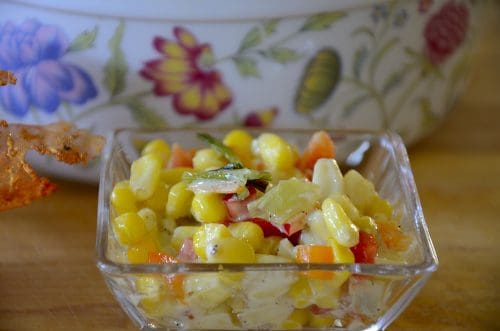 Colourful serving bowl of yellow corn, orange and red peppers and grilled green onions.