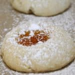 Thumbprint cookies with apricot jam filling on baking sheet.