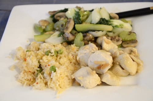 Serving plate with lemoncello chicken, rice, and stir fried baby bok choy with chop sticks.