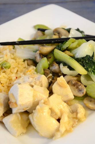 Serving plate with lemoncello chicken, rice, and stir fried baby bok choy with chop sticks.