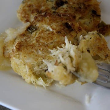 Close up of fried sauerkraut cakes on a plate with a dollop of applesauce.