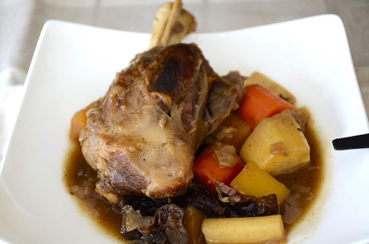 Lamb shanks in Guinness in a bowl with root vegetables.