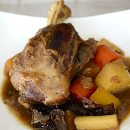 Lamb shanks in Guinness in a bowl with root vegetables.