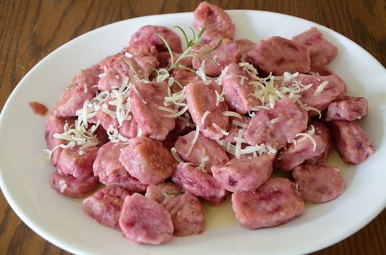 Beet gnocchi, cooked on serving platter with fresh parmesan grated on top.