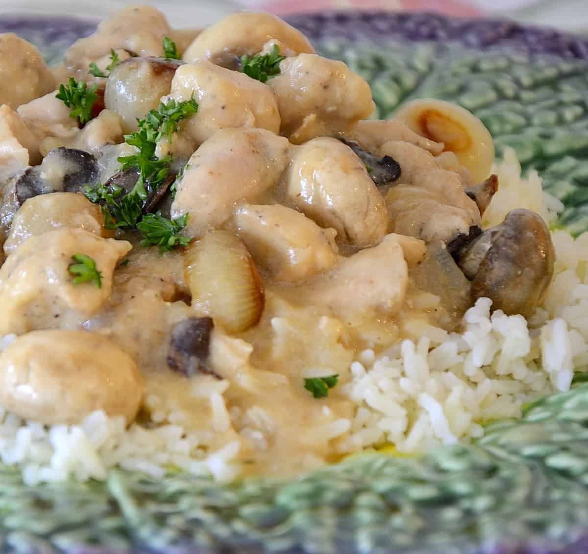 Close up of French rabbit in mustard sauce with pearl onions and mushrooms on a bed of rice.