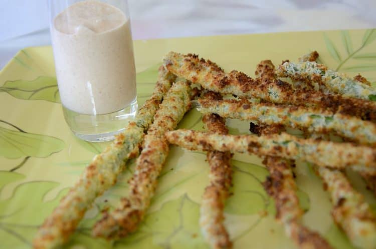 Crispy, breaded asparagus spears on a tray with dipping sauce.