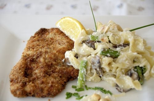 Crispy air fried chicken cutlets with a slice of lemon on a plate.