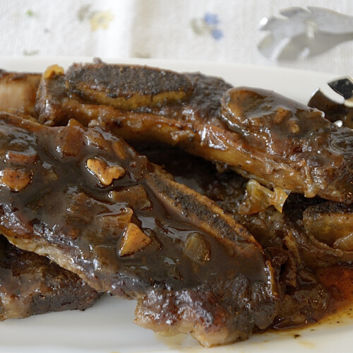 Beef short rib strips on a platter glistening with sweet and sour glaze.