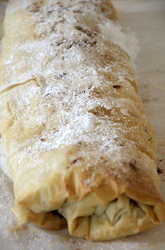 Flaky apple strudel with phyllo pastry topped with icing sugar.