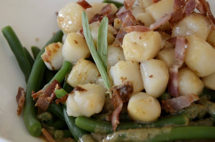 Seared scallop over green beans with bacon bits and creamy bacon dressing.
