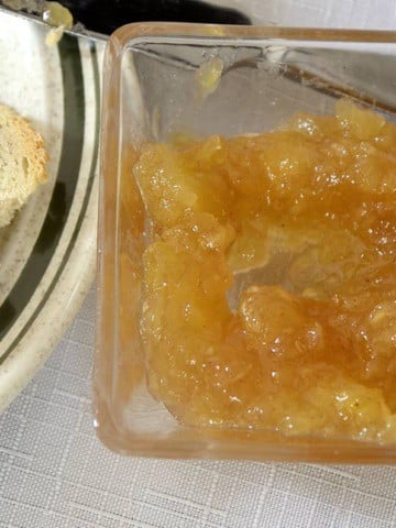 Small bowl of pineapple jam beside toast on a plate.