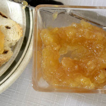 Small bowl of pineapple jam beside toast on a plate.