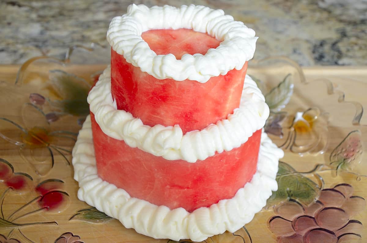 Cream cheese frosting piped on outer edge of each layer and around the base.