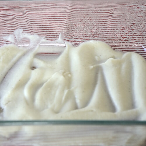 Thick creamy cauliflower bechamel coating the bottom of a baking dish.