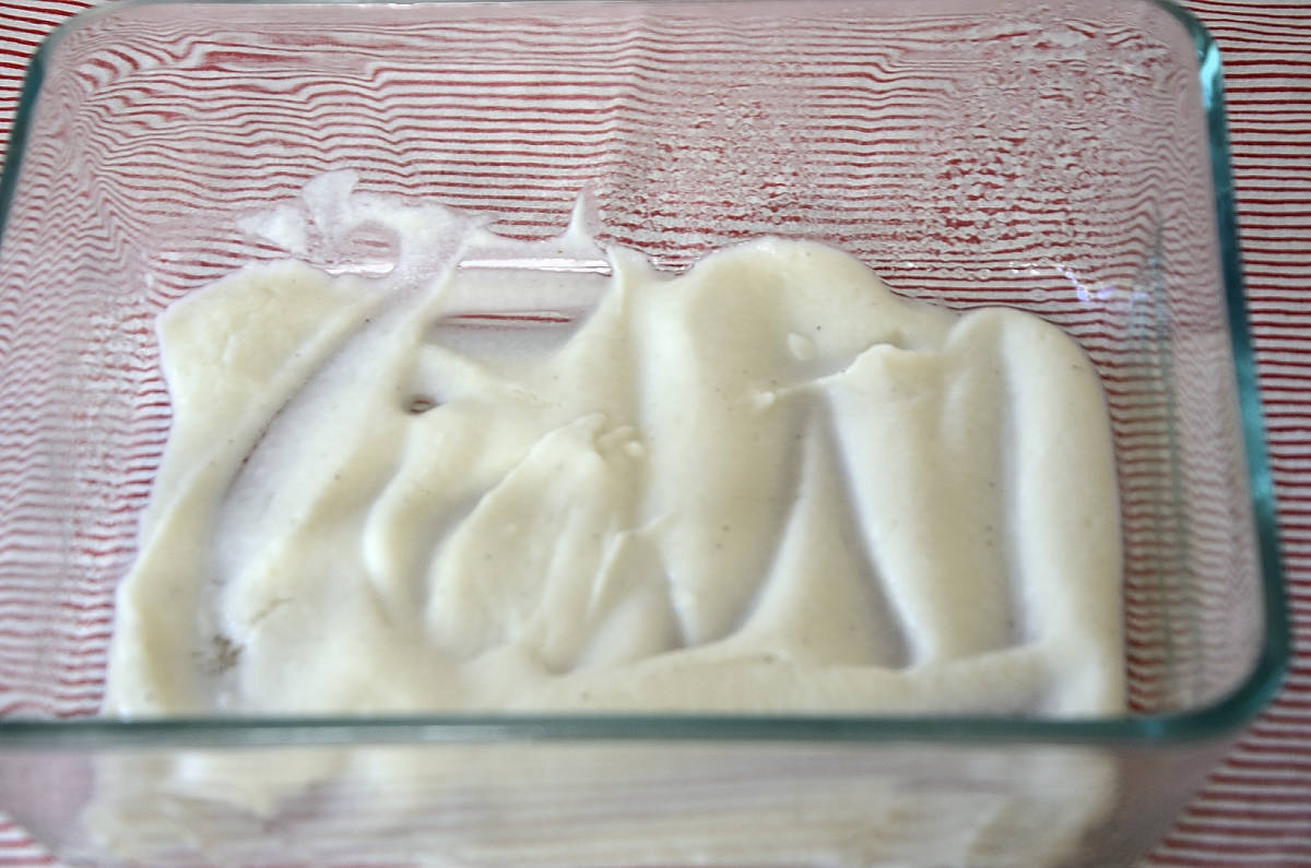 Thick creamy cauliflower bechamel coating the bottom of a baking dish.