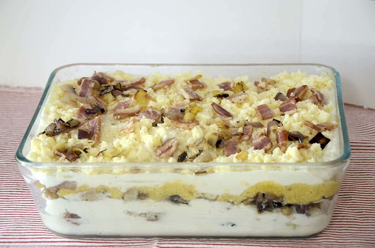 Baking dish of vegetable lasagna showing creamy layers.