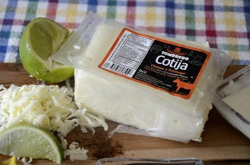 Close up of a package of Cotija cheese with some grated on the side.