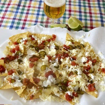 Platter of tortilla chips with cheese, salsa and cream toppings.