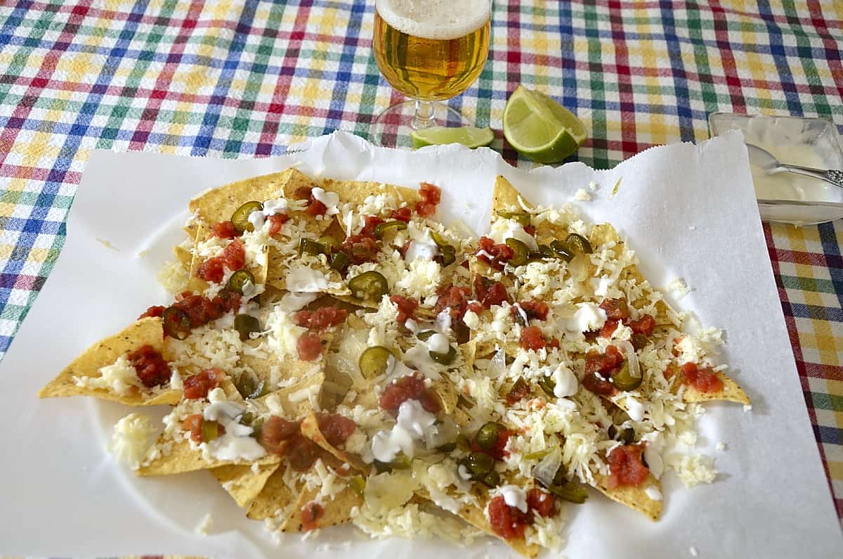 Platter of tortilla chips with cheese, salsa and cream toppings.