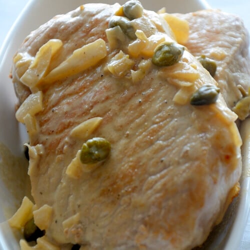 Golden seared pork chop with mustard caper pan sauce.