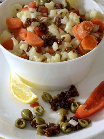 Bowl of chopped cauliflower and carrots with a creamy Italian dressing.