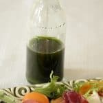 Small clear bottle of vibrant green basil oil.