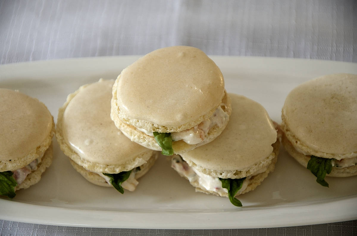 Almond Macarons filled with a feta, cream cheese mixture with tomato and basil, on a plate.