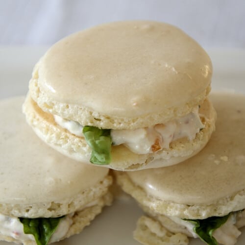 Almond Macarons filled with a feta, cream cheese mixture with tomato and basil, on a plate.