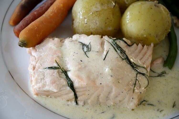 Poached salmon fillet with creamy dill sauce, baby potatoes and heirloom carrots.