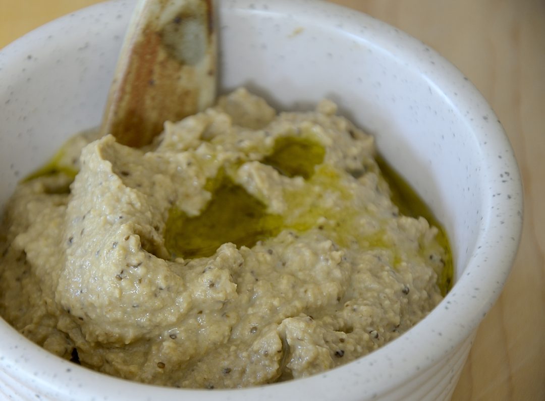 Close up of bowl of creamy eggplant dip with olive oil drizzled on top.