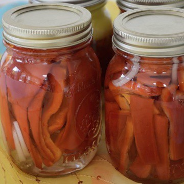 Pickled sweet peppers in pint jars with onion slices.