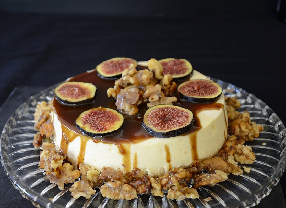 Creamy, cheesecake with balsamic caramel drizzled on top, garnished with fresh fig slices and candied walnuts.