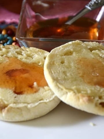 English muffin with jewel-tonedprickly pear jam on it, with a pot of jam in background.