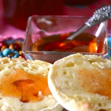 English muffin with jewel-tonedprickly pear jam on it, with a pot of jam in background.