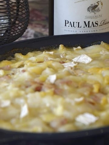 Casserole dish of creamy diced potatoes swimming in a creamy brie sauce.