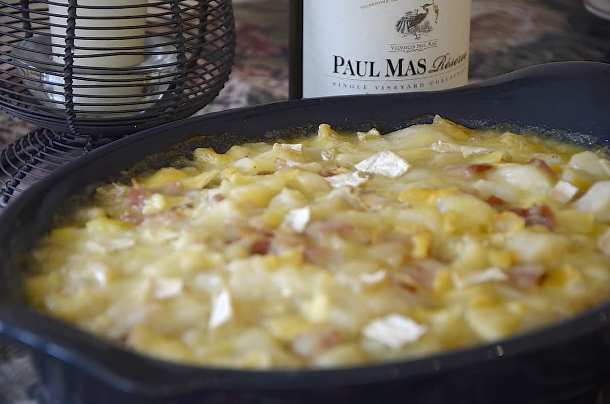 Casserole dish of creamy diced potatoes swimming in a creamy brie sauce.