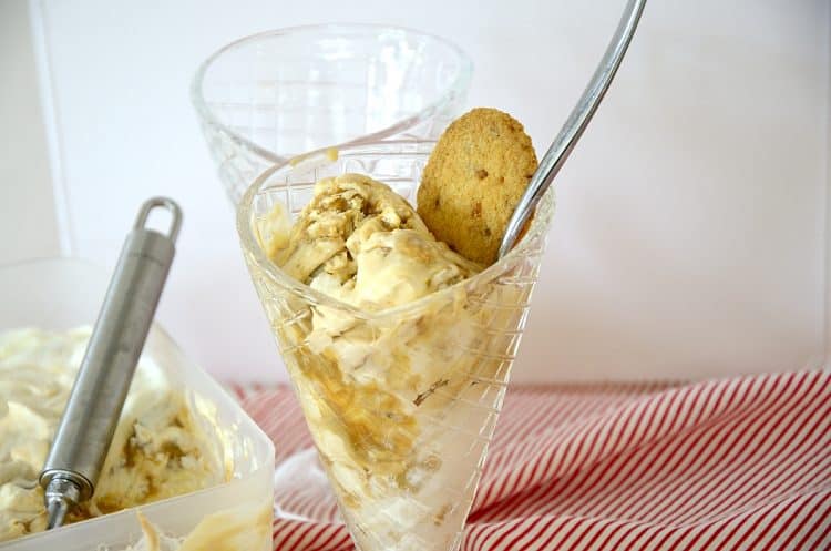 Scoops of Dulce de Leche flavoured ice cream in a cup with a cookie for garnish.