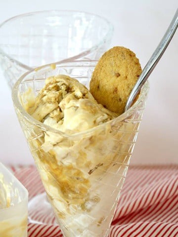 Scoops of Dulce de Leche flavoured ice cream in a cup with a cookie for garnish.