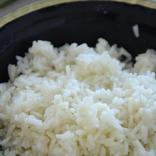 White rice in a black bowl that was cooked in the air fryer.