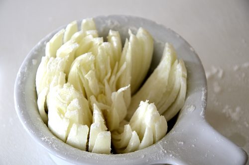 Blooming onion cut into slices in a small container.