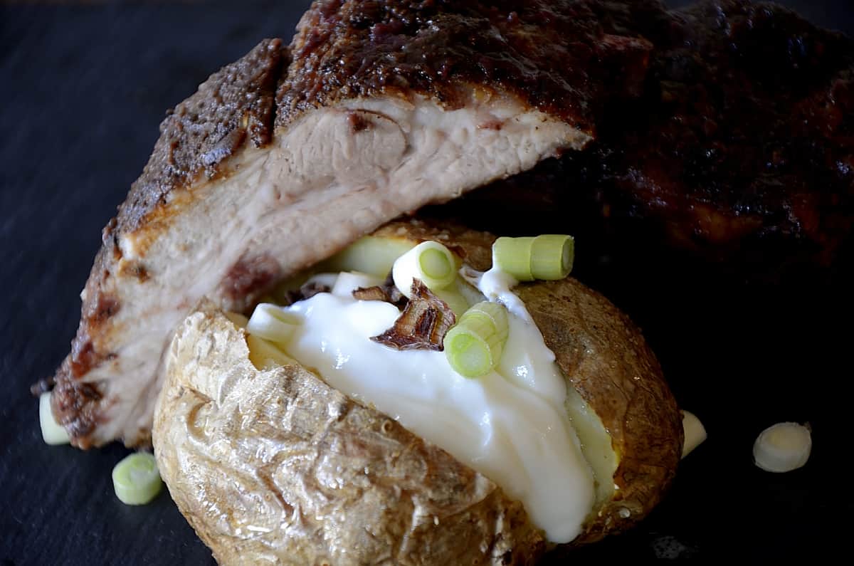 Crispy baked potato split open with sour cream and green onion toppings.