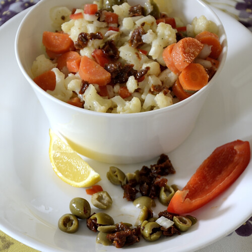 Bowl of chopped cauliflower and carrots with a creamy Italian dressing.