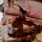Rare roast beef sliced on a platter drizzled with Bordelaise Sauce.