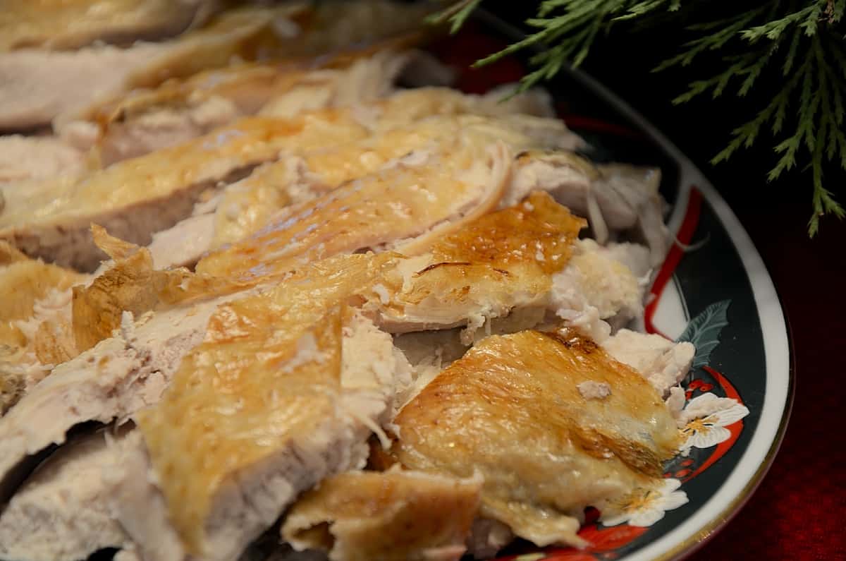 Sliced turkey breast with golden crispy skin on a serving platter.
