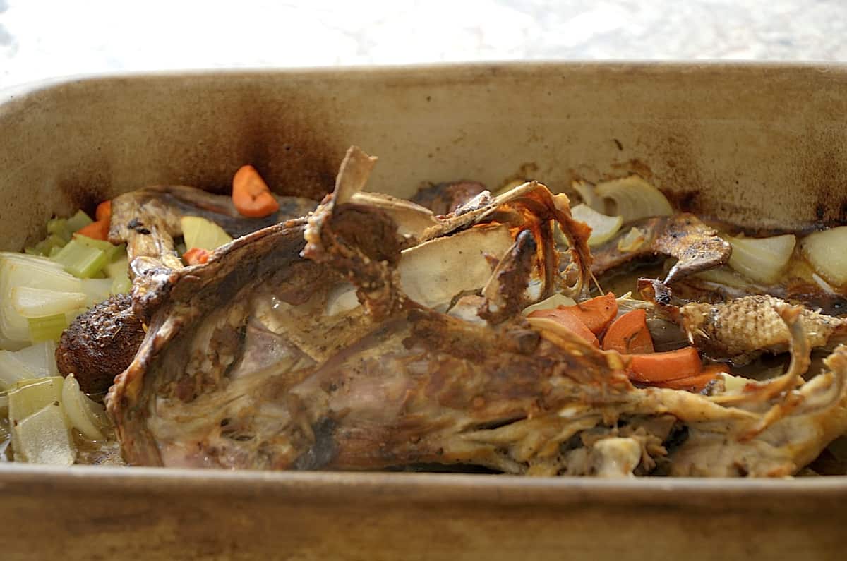 Roasted duck carcass in roaster with vegetables.