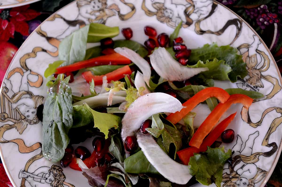Fennel pomegranate salad on plate with red pepper slices and pomegranate arils.