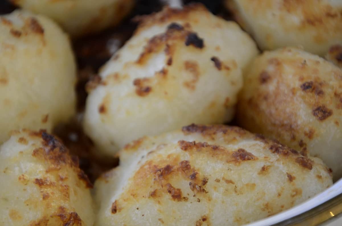 Crispy, roasted, whole potatoes on a serving plate.