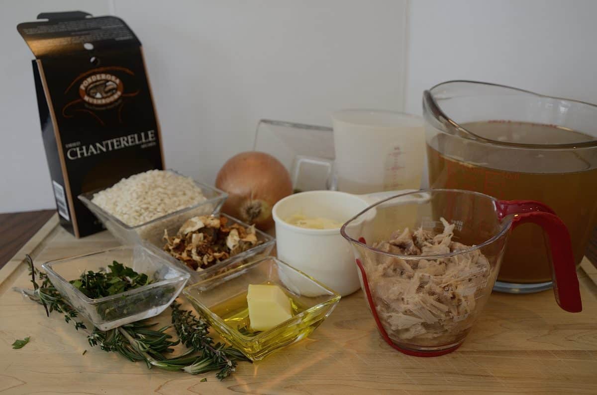 Ingredients for duck risotto including broth, rice, dried mushrooms, onion, oil, cheese and white wine.