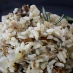 A scoop of creamy risotto studded with wid mushrooms and duck meat and garnished with fresh grated paremsan cheese and herbs.