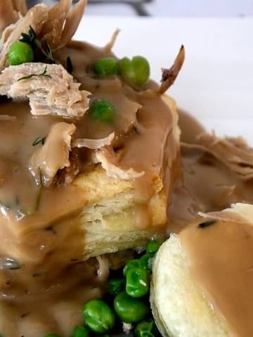 Leftover turkey bits in a puff pastry shell with Turkey Marsala Gracy drizzele over it and peas on the side.